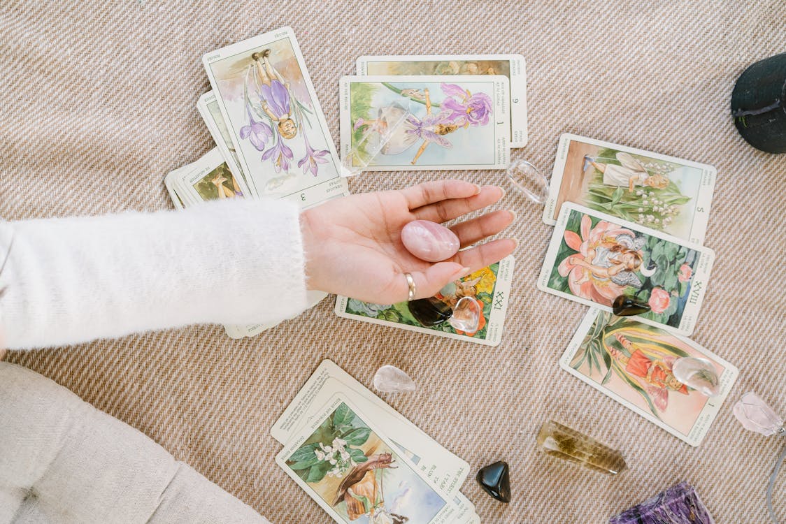 Tarot cards spread on the floor while a hand holds a crystal